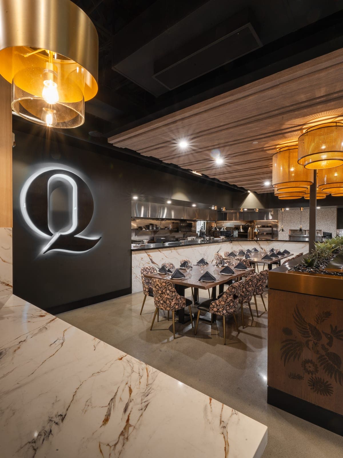 Una Q iluminada en un muro oscuro junto al comedor