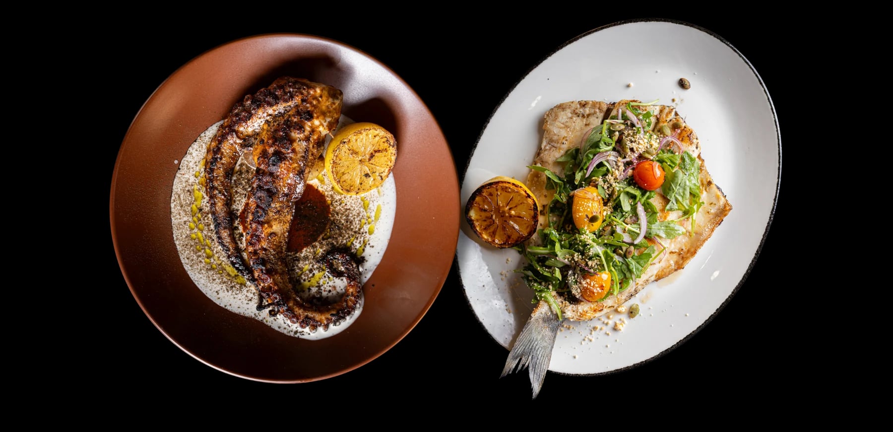 Grilled octopus on a terracotta plate beside a whole grilled fish on an oval plate