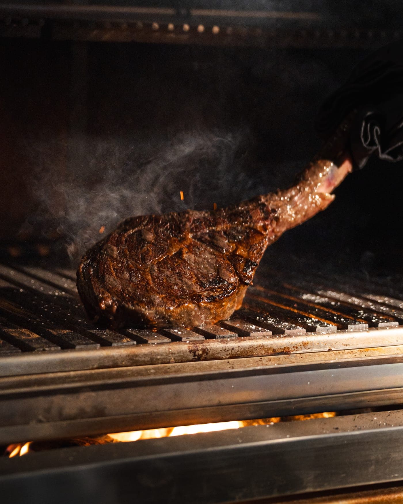 Un tomahawk en la parrilla mientras sube el humo