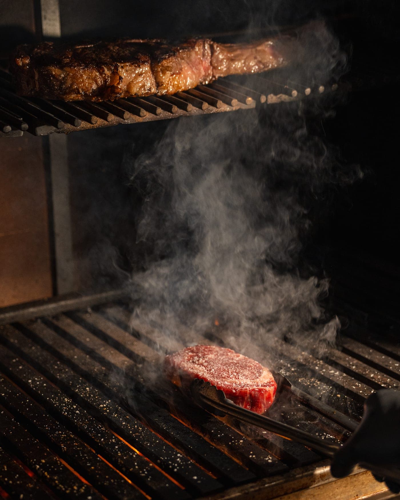 Un corte sellándose en la parrilla entre el humo