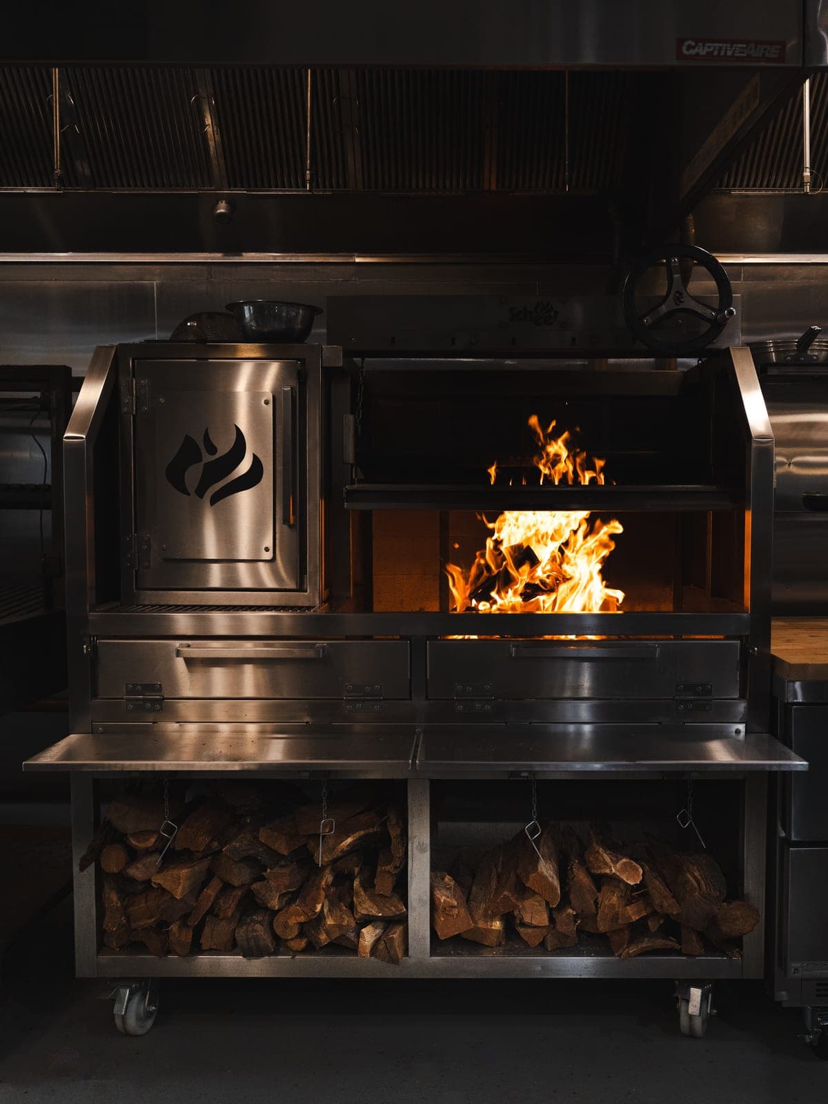 The wood-fire grill with firewood stacked below